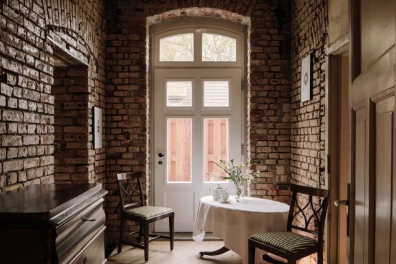Gemütlicher Eingangsbereich mit Backsteinwänden, Tisch und zwei Stühlen.