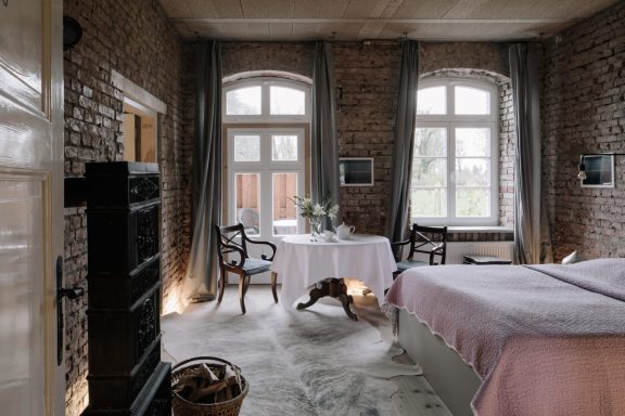 Gemütliches Schlafzimmer mit Ziegelwänden, Tisch, Stühlen und einem Hund.