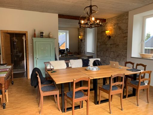 Geräumiger Essbereich mit Holztafel, Stühlen und gemütlicher Beleuchtung.